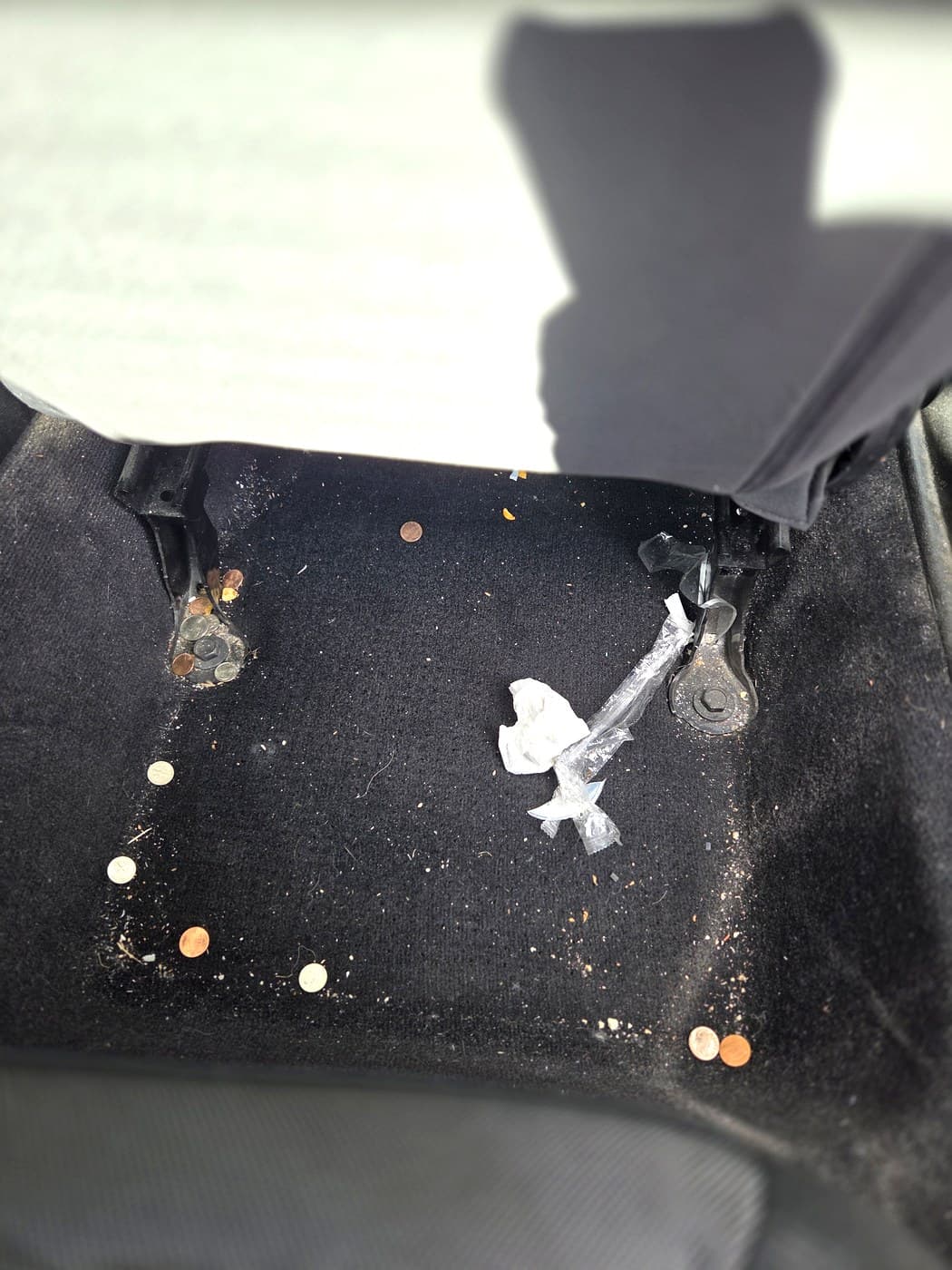 Rear under-seat area before cleanup with crumbs and debris visible.